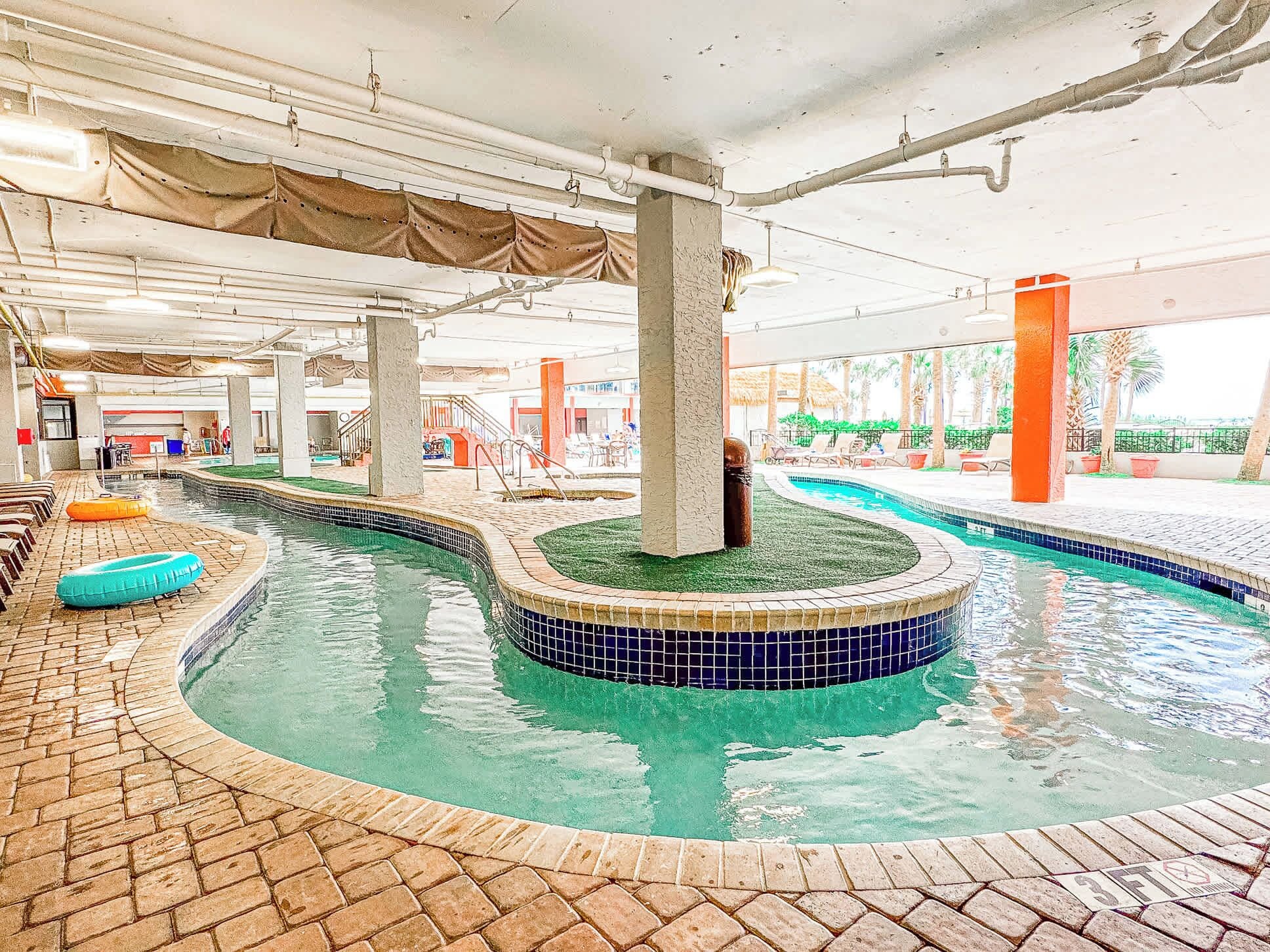 Une piscine intérieure dotée de plusieurs couloirs, d’un sol en briques et d’un espace couvert avec des sièges.