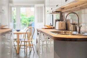A modern kitchen with a stainless steel sink, wooden countertop, and a view of the outdoors.