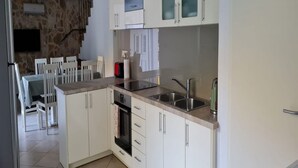 Una cocina moderna con armarios blancos, encimera de granito, horno empotrado y pileta de acero inoxidable.