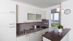 Una cucina moderna con mobili bianchi, un piano di lavoro scuro, un lavello, un fornello e una finestra con vista.