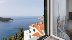 Una stanza con vista sul mare, una tenda legata al telaio della finestra e un condizionatore Samsung.