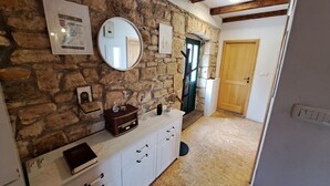 Une pièce avec un mur en pierre, une porte en bois, une armoire blanche et un miroir.