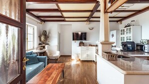 Un espace de vie compact comprenant un banc en bois, un canapé, un téléviseur et un coin cuisine.