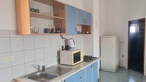 Een keuken met een spoelbak, een magnetron, een fornuis en een koelkast.