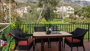 Une terrasse extérieure couverte, avec une table et des chaises, une bouteille de vin et des verres.
