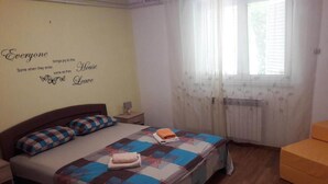 A bedroom with a bed, a nightstand, a window with sheer curtains, and a wall with a quote. - Apartments Amalia - Two Bedroom Apartment with Terrace (Zadar)