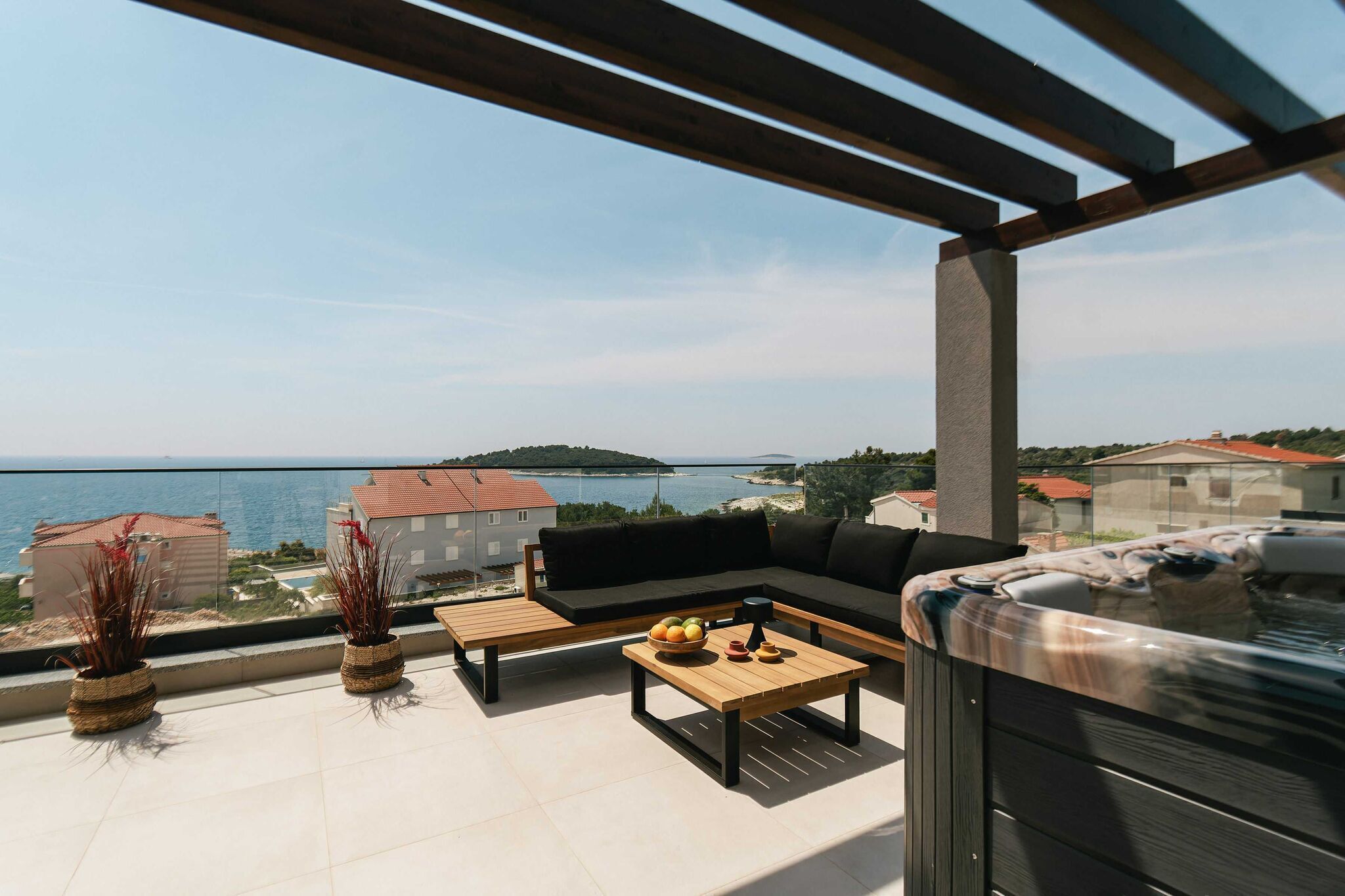 Ein Balkon mit einer Couch, einem Couchtisch und einer Whirlwanne.