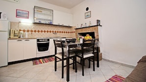 Une cuisine compacte avec des meubles blancs, une cuisinière, un lave-vaisselle et une table à manger avec des chaises.