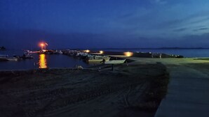 A marina at dusk with boats docked and a light illuminating the water. - Dalmatino Pleasure Mobile Home - Two Bedroom Mobile Home with Terrace (Privlaka)