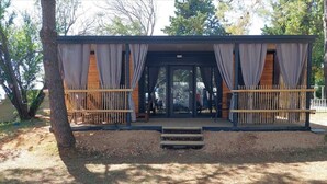 A wooden structure with a covered entrance, a bench, and a small staircase leading up to it. - Dalmatino Pleasure Mobile Home - Two Bedroom Mobile Home with Terrace (Privlaka)