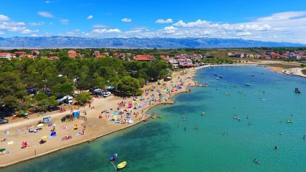 A coastal town with a beach, clear blue waters, and mountains in the background. - Dalmatino Pleasure Mobile Home - Two Bedroom Mobile Home with Terrace (Privlaka)