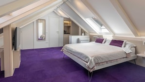Un dormitorio con techo inclinado, una cama con cabecera morada y una alfombra morada.