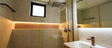A modern bathroom with a large mirror, a shower area, and a bathtub.