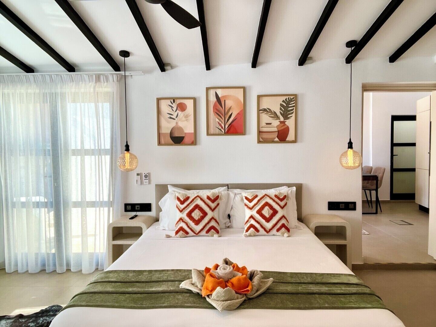 Habitación de hotel moderna con cama, mesitas de noche, obras de arte en las paredes y vistas al exterior.