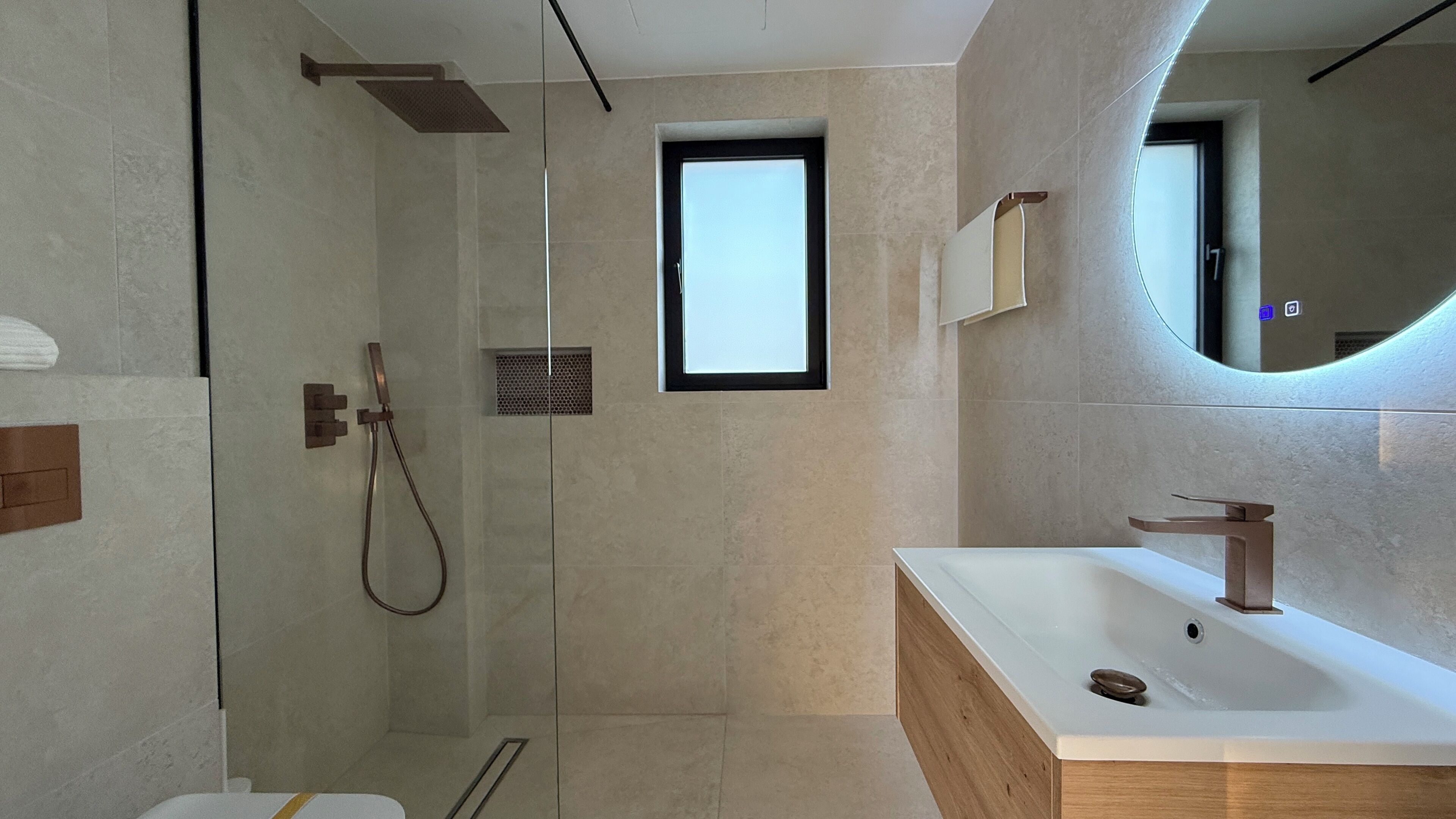 A modern bathroom with a glass shower enclosure, a wooden vanity, and a large mirror.