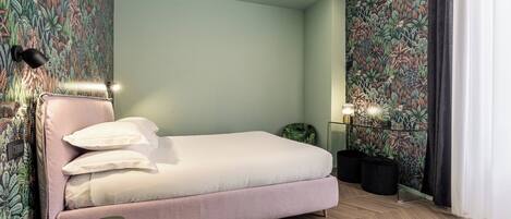 Une chambre à coucher comprenant un lit, une chaise, une table de chevet et un mur orné d’un motif floral.