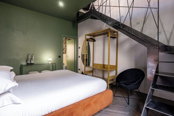A modern bedroom with a large bed, a wooden chair, a mirror, and a staircase. - Residenza Madiba (Florence)