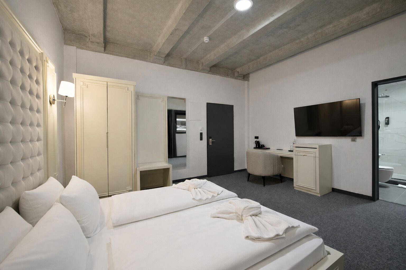 Een hotelkamer met een groot bed, een bureau, een televisie en een garderobe.