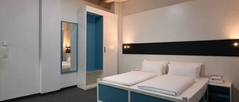 Une chambre d’hôtel moderne avec un grand lit, une armoire, un miroir et une table de chevet.