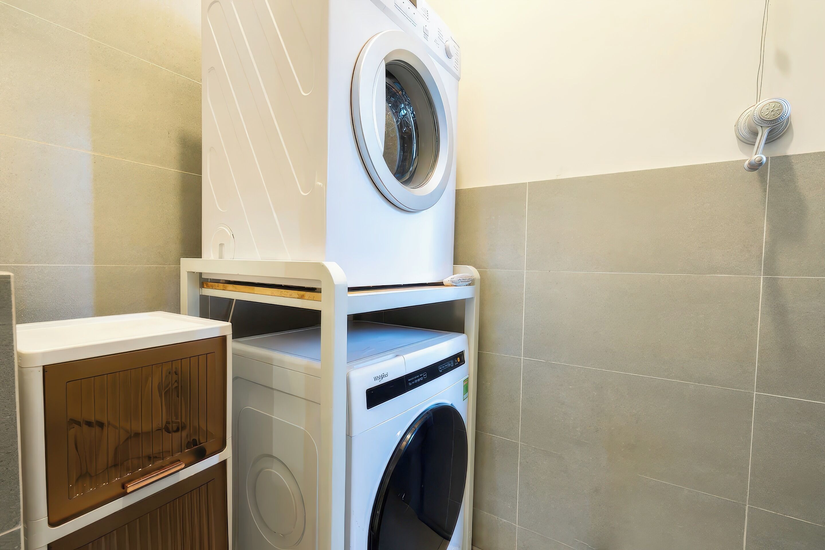 A compact laundry area with a front-loading washer and dryer, a wooden cabinet, and a wall-mounted towel rack.