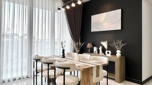 Un comedor moderno con una mesa de madera, sillas blancas y una pared de acento negra.