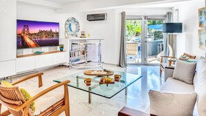 A modern living room with a glass coffee table, a sofa, and a TV displaying a cityscape. - Waterfront Oasis / Cascading Pool & Views / Centrally located / Heated Pool / Cascade Key/Residences (Fort Lauderdale)