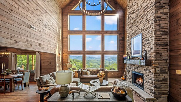 A spacious living room with a stone fireplace, large windows offering a mountain view, and a cozy seating area.