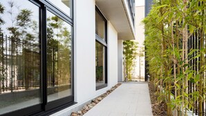 Un edificio moderno con grandes ventanales, un sendero y plantas de bambú.