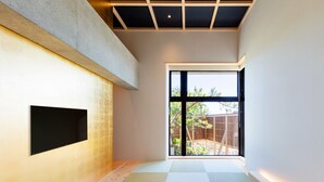 Un interior moderno con un ventanal grande, un televisor montado en la pared y suelo de madera.