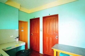 A hallway with two wooden doors, a small counter with a trash bin, and a sign indicating room number 31. - RedDoorz @ D128 Lodge Cagayan Valley (Tuguegarao)