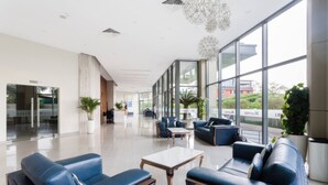 A spacious lobby with modern seating, large windows, and a clean, polished floor. - Genius Saigon - Masteri Thao Dien District 2 (Ho Chi Minh City)