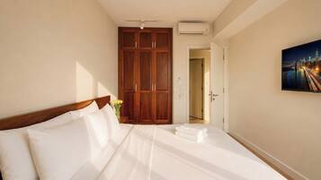 Une chambre d’hôtel avec un grand lit, une armoire, un appareil de climatisation et un tableau représentant un paysage urbain accroché au mur.
