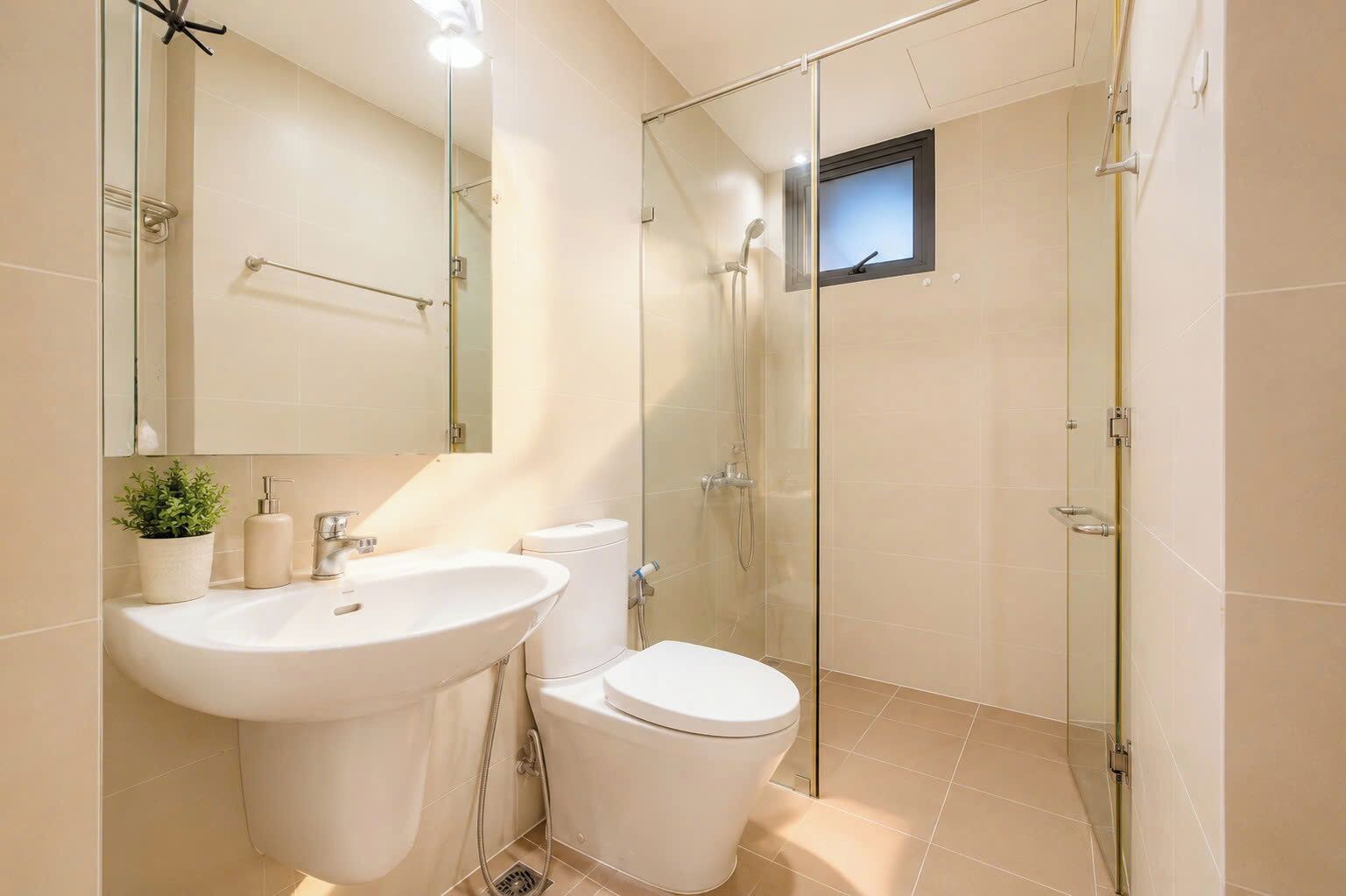 A modern bathroom with a glass-enclosed shower, a white sink, and a toilet.