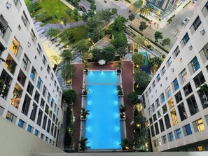 A modern building with a central swimming pool surrounded by greenery and balconies. - Genius Saigon - Masteri Thao Dien District 2 (Ho Chi Minh City)