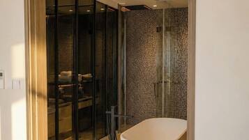 A modern bathroom with a freestanding bathtub, a glass shower enclosure, and a visible bathroom counter.