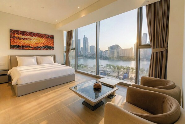 A modern hotel room with a large bed, a glass coffee table, and a view of a cityscape. - The Opera Residence - Pool & Sauna (Ho Chi Minh City)