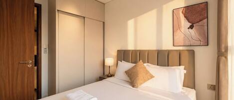 A hotel room with a bed, a nightstand, a wall-mounted artwork, and a wooden door.