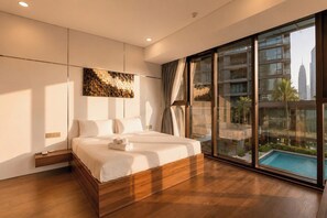 Ett modernt hotellrum med en stor säng, utsikt över en swimmingpool och en stadsutsikt genom fönster som sträcker sig från golv till tak.