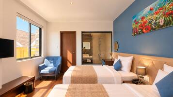 Habitación de hotel con dos camas, ducha, televisor y un cuadro en la pared.