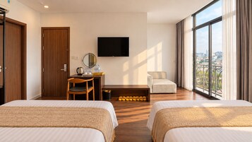 Ett hotellrum med två sängar, ett skrivbord med en stol, en tv och utsikt över staden genom stora fönster.