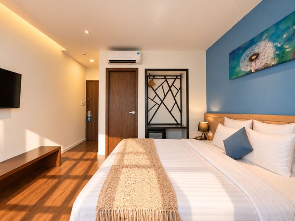 A hotel room with a bed, a TV, a painting, and a door.