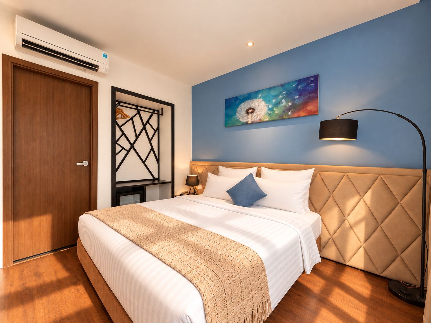 Una habitación de hotel con cama, mesita de noche, lámpara de pared y un cuadro.