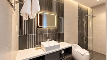 A modern bathroom with a vanity, a mirror, a shower, and a toilet.