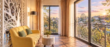 A modern living room with a yellow sofa, a round coffee table, and a view of a cityscape through large windows.