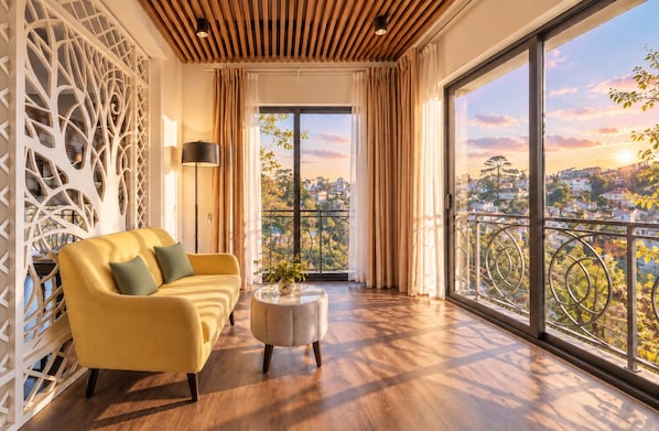 Una sala de estar moderna con un sofá amarillo, una mesa de centro redonda y vistas de un paisaje urbano a través de amplios ventanales.