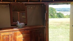 Een houten dressoir met een glazen schaal, een spiegel en een klein schilderij.