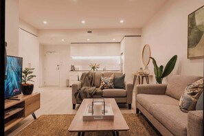 Uma sala de estar moderna com sofá, mesa de centro e televisão.