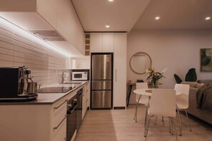 Uma cozinha moderna com micro-ondas integrado, frigorífico em aço inoxidável e máquina de café.