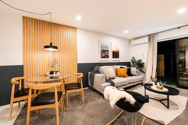 Een moderne woonkamer met een glazen eettafel, een bank en een bijzettafeltje.