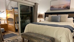 A bedroom with a bed, a bench, a chair, a lamp, and a picture on the wall. - Beautiful and beachy condo (Sanibel)